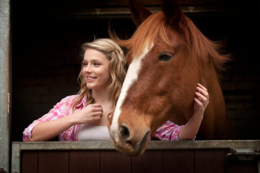 Young woman petting a horse during equine therapy for addiction treatment.