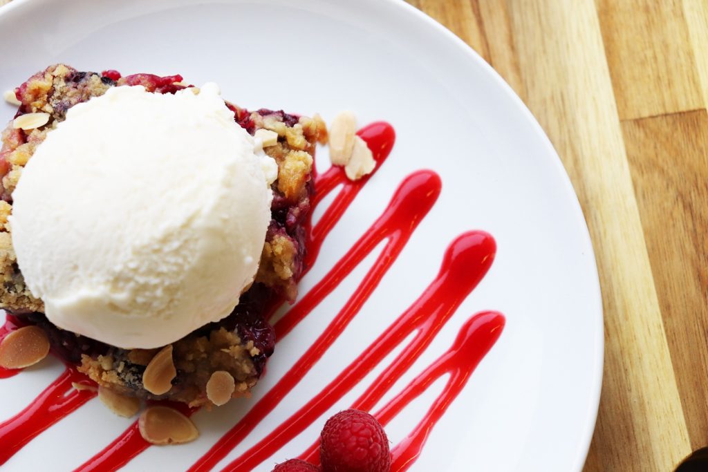 Blackberry Crumble | Topped with ice cream and served over raspberry coulis with fresh raspberries